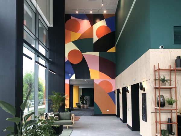 A vibrant mural featuring various colors and patterns adorns the lobby wall, creating an inviting atmosphere.
