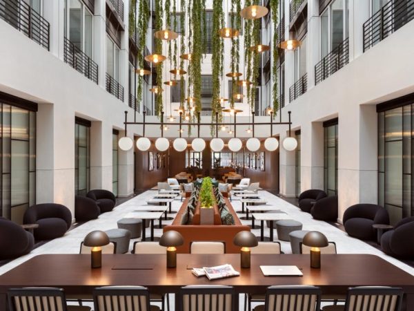The hotel atrium features a long table surrounded by chairs, creating a welcoming gathering space for guests.