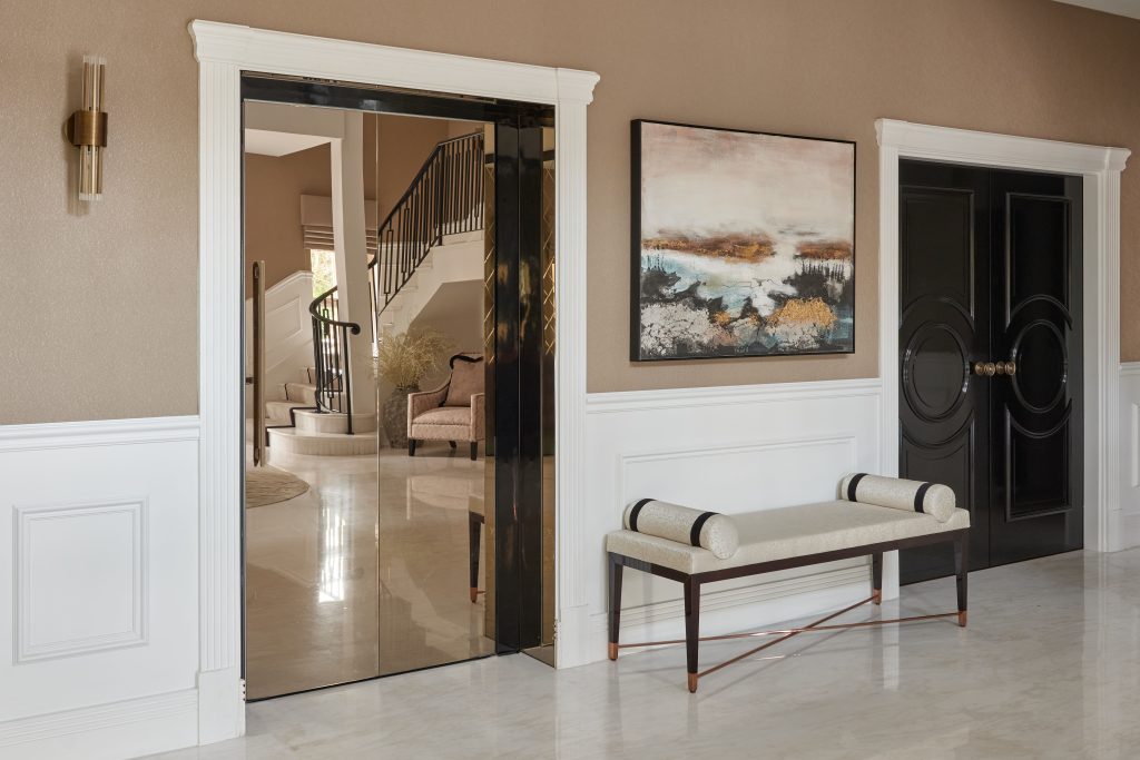 A hallway featuring a large mirror on the wall and a wooden bench against the side