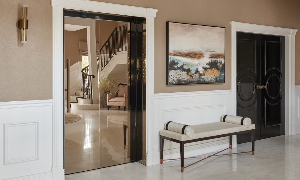 A hallway featuring a large mirror on the wall and a wooden bench against the side