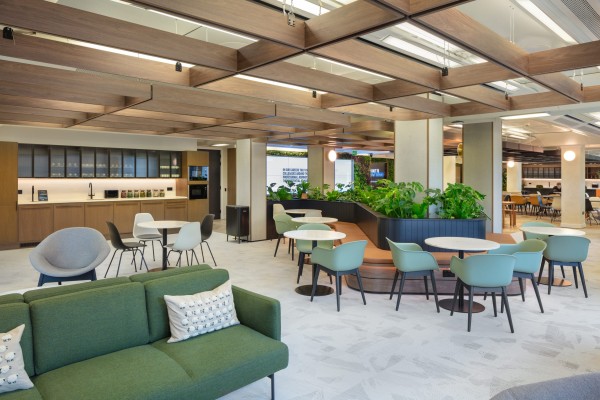 Office lobby featuring green couches and tables, creating a welcoming and comfortable atmosphere for visitors.