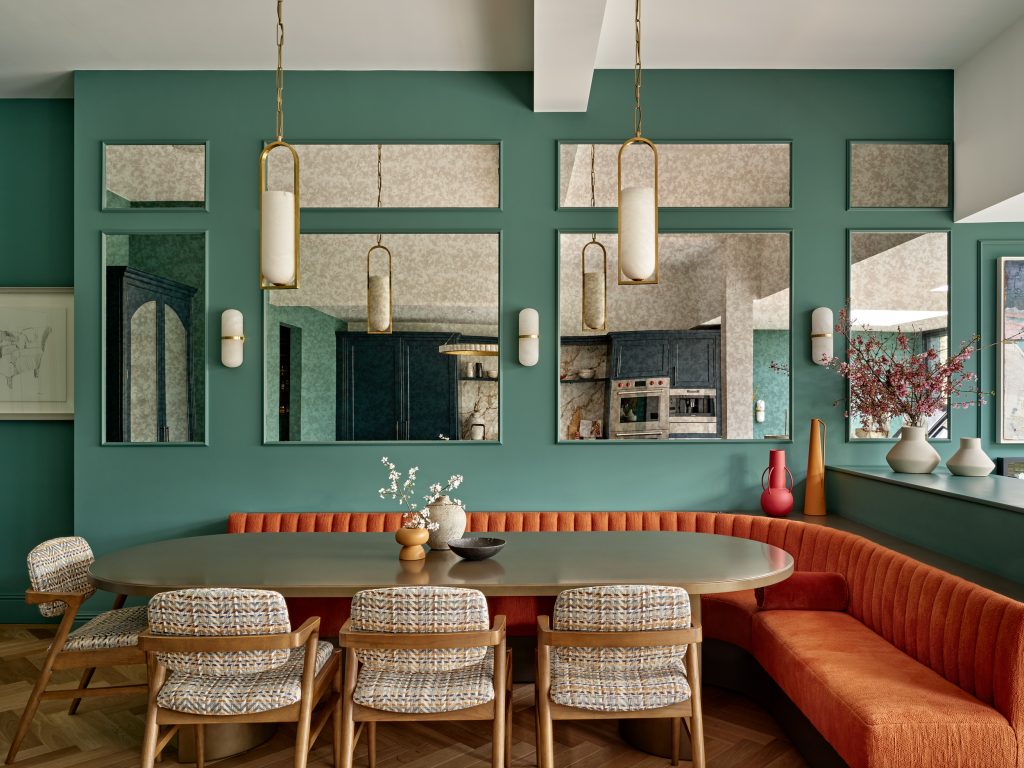 A dining room with vibrant green walls and bright orange chairs, creating a lively and inviting atmosphere.