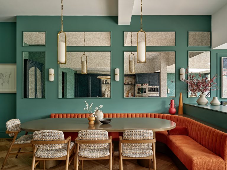 A dining room with vibrant green walls and bright orange chairs, creating a lively and inviting atmosphere.